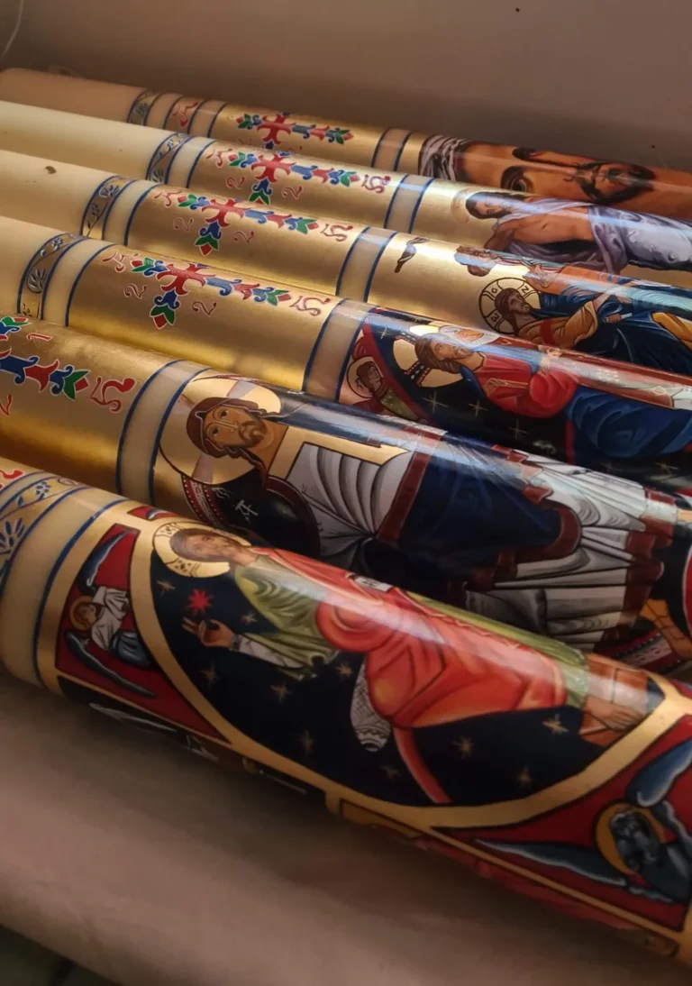 Varios cirios pascuales 2027 pintados a mano con pan de oro, listos en el taller